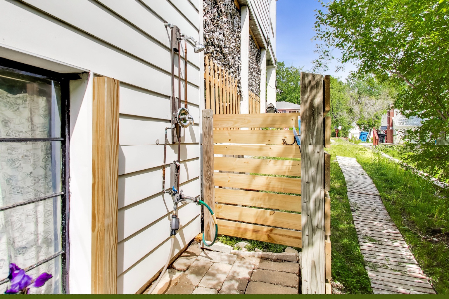 Private outdoor shower beside the cottage, enclosed by a wooden privacy screen