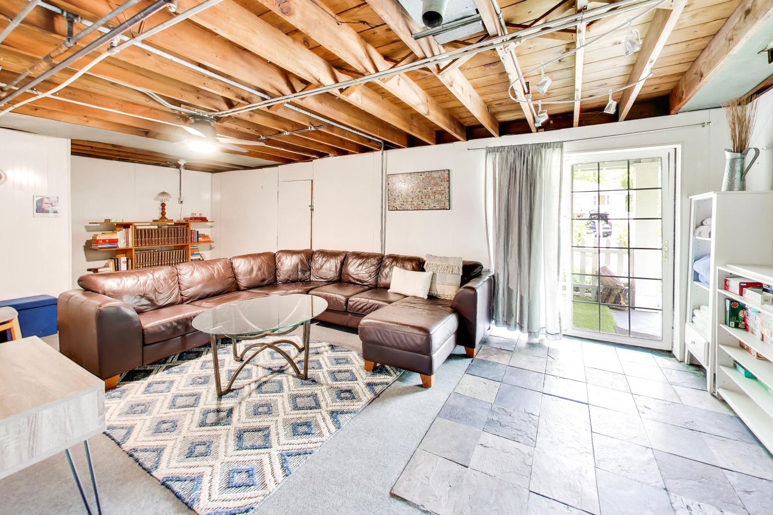 Lower-level recreation room at Emmet’s Place with a sectional sofa, exposed beams, and patio doors